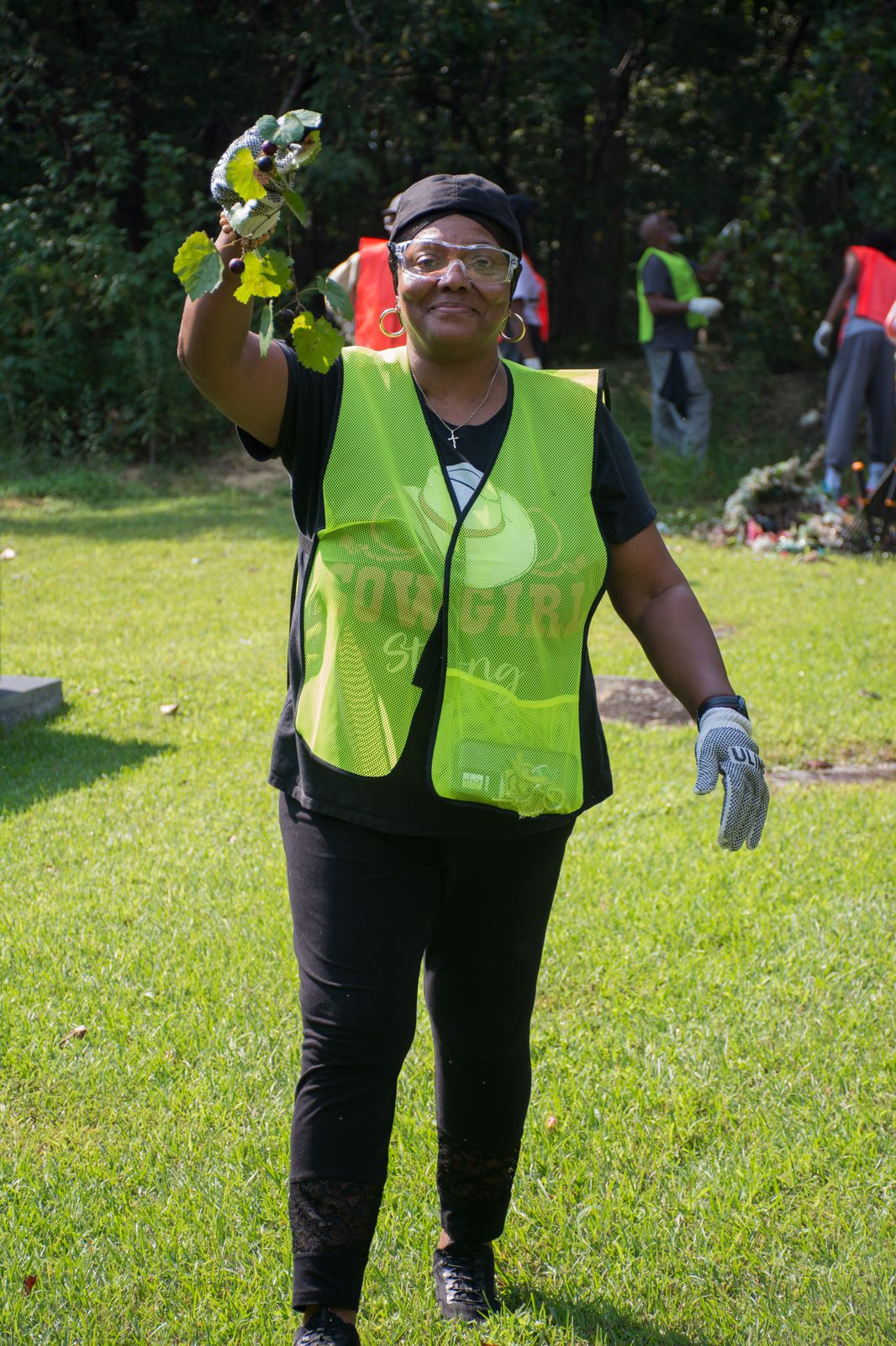 Volunteer holding up a branch while working during Snow Hill Cemetery clean-up