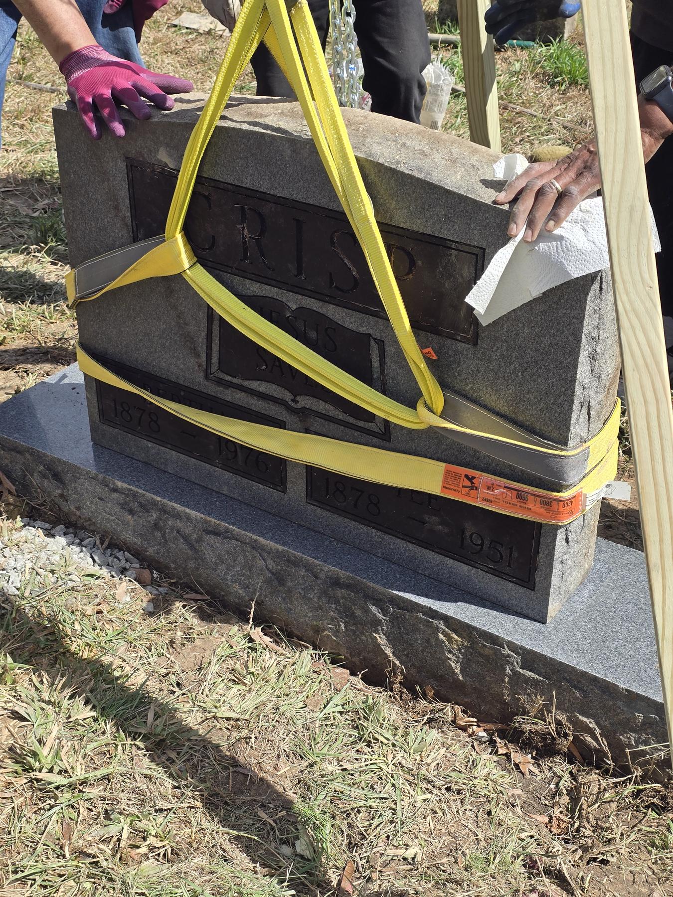 Hands cleaning the Crisp family headstone during restoration