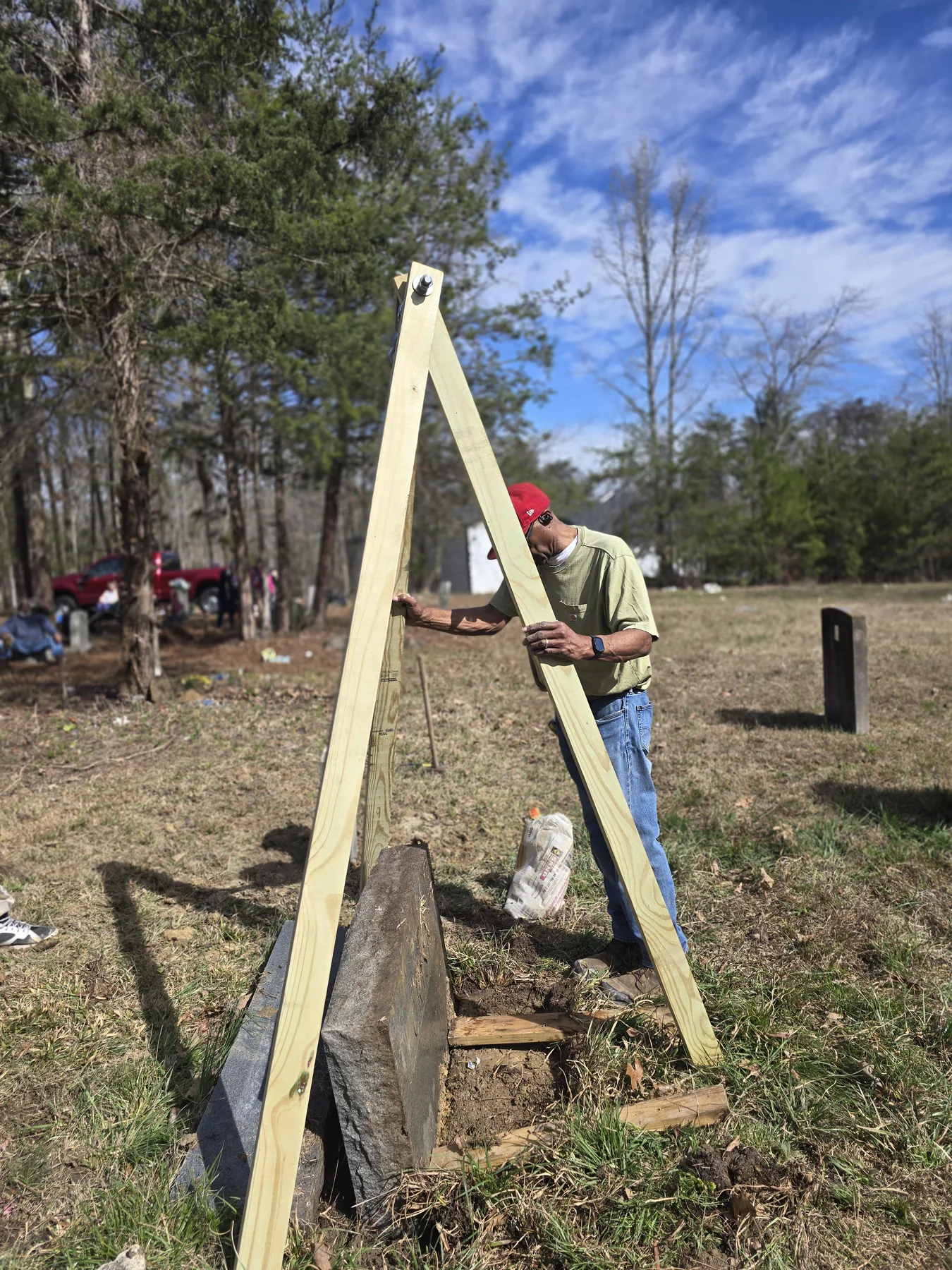 President Mike Woods demonstrating tripod setup and training volunteers during headstone restoration