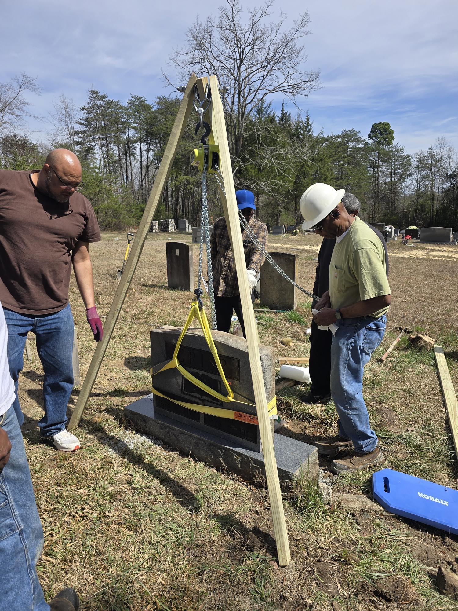 Volunteers gathered around the tripod set up over a historic headstone
